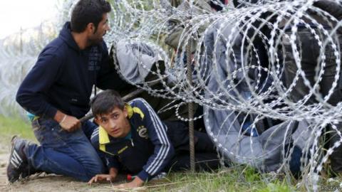  ! 150826072744__syrian_migrants_cross_under_a_fence_at_hungarian-serbian_border_near_roszke__640x360_reuters_0.jpg?itok=iNoiexXl